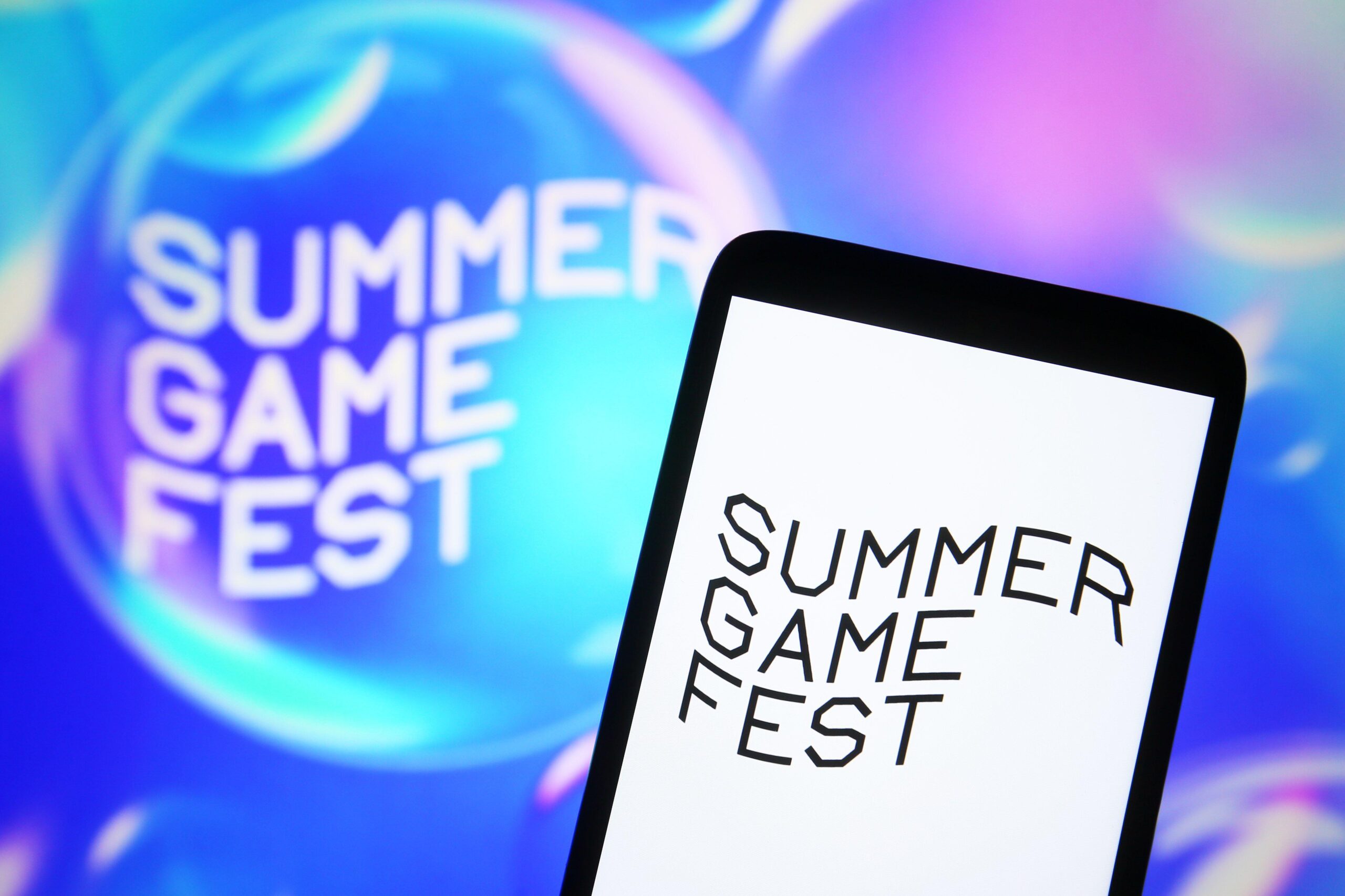 a Summer Game Fest logo on a phone and the wall to represent the day and place Mafia: The Old Country got announced