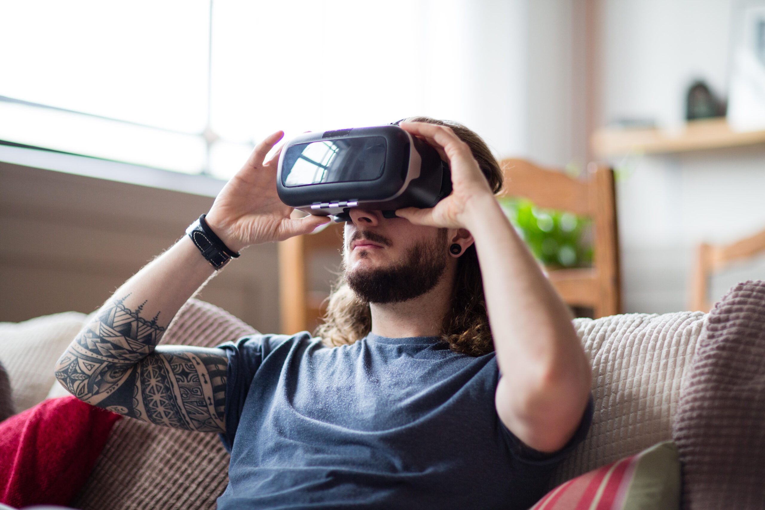 a man sitting on a couch in his home playing Chrono Weavers on his VR